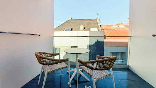 To stole og et bord på en altan med udsigt til hustage. (AI-genereret tekst)