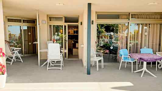 Billede af to terrasser med siddepladser foran glasdøre, der fører ind til lejligheder. (AI-genereret tekst)