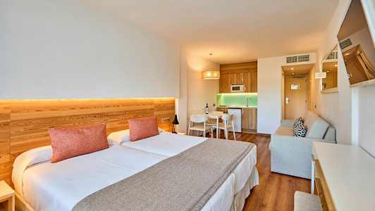 Indretning af et hotelværelse med dobbeltseng, køkkenområde og siddeplads. (AI-genereret tekst)