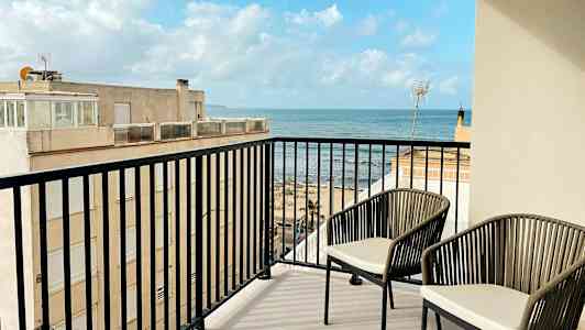 En altan med to stole og udsigt over havet. (AI-genereret tekst)