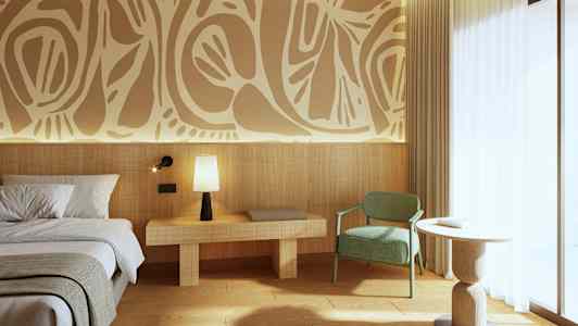 Billede af et moderne hotelværelse med dekorativ kunst på væggen. Der er en seng til venstre, et natbord med en lampe, en grøn stol og et rundt bord tæt på et stort vindue. (AI-genereret tekst)