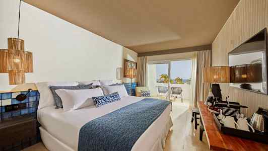 Hotelværelse med stor seng, moderne indretning og balkon med udsigt. (AI-genereret tekst)