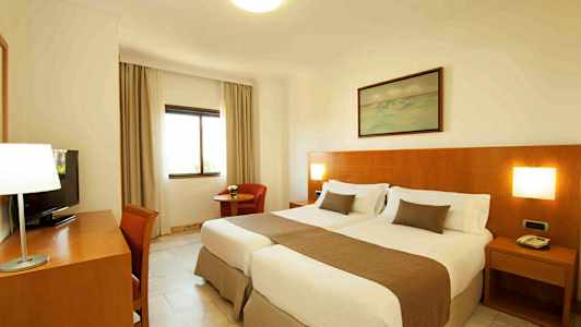 Et hotelværelse med to enkeltsenge og træpanel på væggen. (AI-genereret tekst)