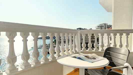 En altan med udsigt over havet, et rundt bord og en sort stol. (AI-genereret tekst)