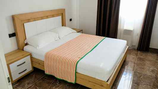 Et soveværelse med en dobbeltseng med træramme, to puder og et stribet sengetæppe. (AI-genereret tekst)