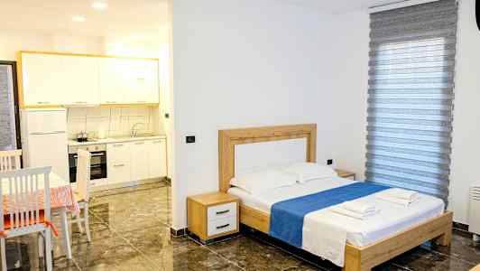 Et soveværelse med en dobbeltseng, bord med stole og en lille køkkenafdeling. (AI-genereret tekst)