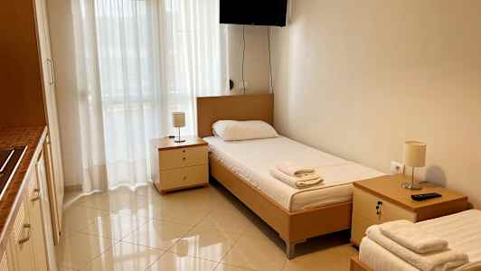 Et værelse med to enkeltsenge, sideborde og et vægmonteret tv. (AI-genereret tekst)