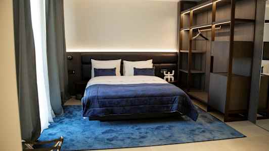 Et komfortabelt hotelværelse med en dobbeltseng, blå sengelinned og stilfuld indretning. (AI-genereret tekst)