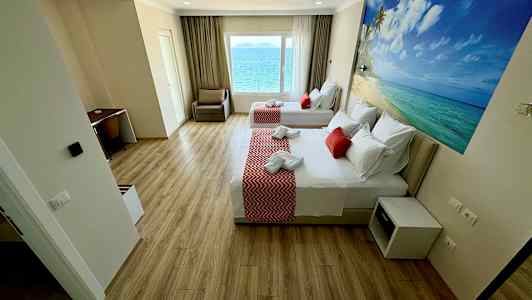 Et hotelværelse med to senge, skrivebord og havudsigt fra vinduet. (AI-genereret tekst)