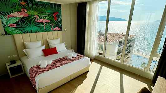 Soveværelse med stor seng, flamingomotiv på væggen og havudsigt gennem panoramavinduer. (AI-genereret tekst)