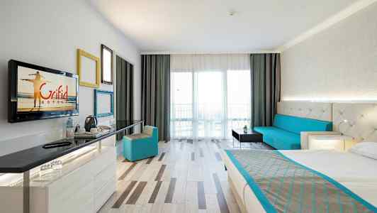 Et hotelværelse med en seng, en siddegruppe, et skrivebord og en altan. (AI-genereret tekst)