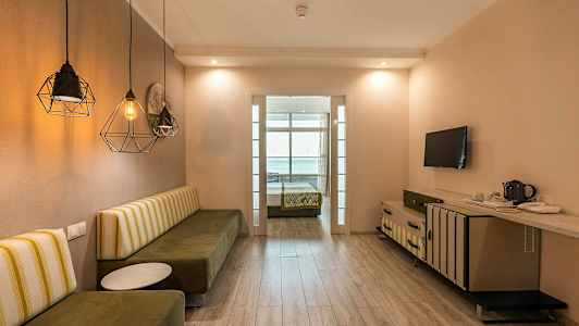 Et hotelværelse med en bænk, bord, TV og en seng i baggrunden. (AI-genereret tekst)