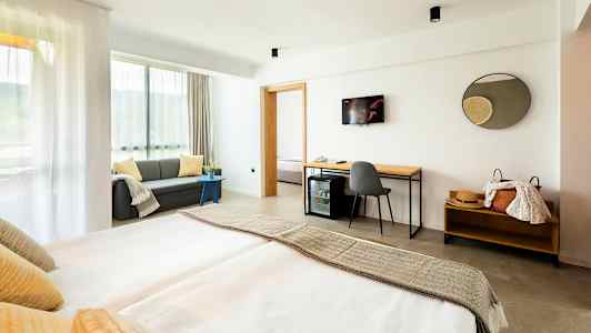 Moderne hotelværelse med dobbeltseng, sofa og skrivebord. (AI-genereret tekst)