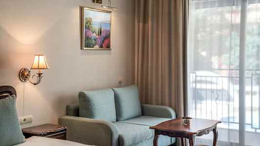 Interiør af et hotelværelse med sofa, bord og seng. (AI-genereret tekst)