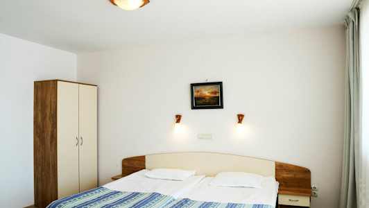 Et hotelværelse med en dobbeltseng, natbord og klædeskab. (AI-genereret tekst)