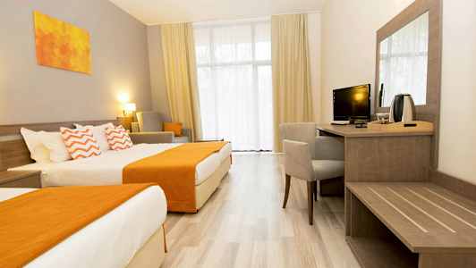 Et hotelværelse med to senge, et skrivebordshjørne og siddepladser. (AI-genereret tekst)