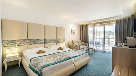 Hotelværelse med dobbeltseng, sofa og balkon. (AI-genereret tekst)