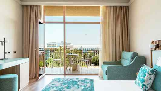 Hotelværelse med dobbeltseng, turkis indretning og altan med udsigt. (AI-genereret tekst)