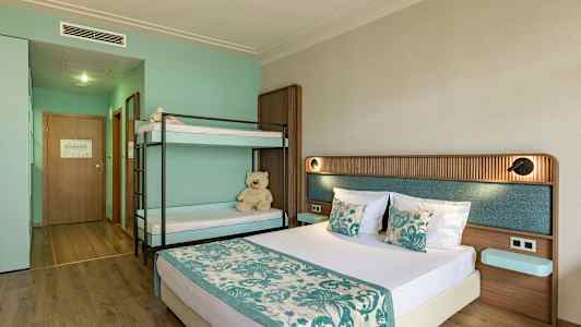 Et hotelværelse med en dobbeltseng og en køjeseng, indrettet i turkis og beige farver. (AI-genereret tekst)