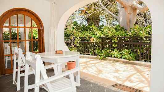 En terrasse med hvide træmøbler og frodige planter. (AI-genereret tekst)