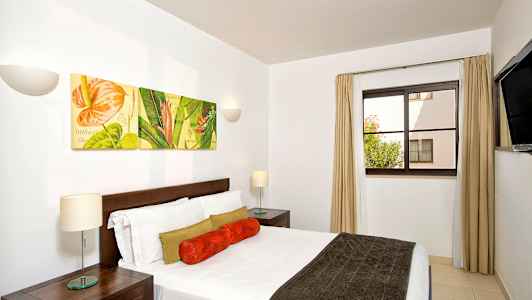 Et soveværelse med en dobbeltseng og vægdekorationer, der viser blomsterbilleder. (AI-genereret tekst)