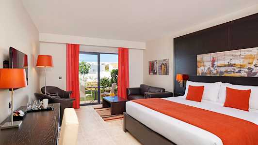 Hotelværelse med seng, sofa og udsigt til en have. (AI-genereret tekst)