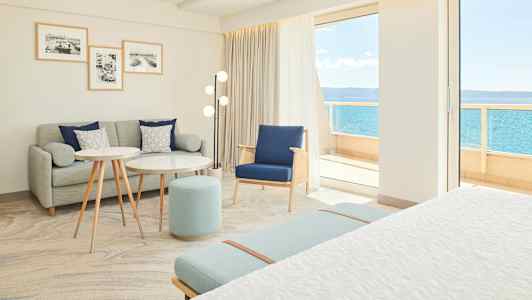 Lyst og moderne hotelværelse med siddeområde og udsigt til havet. (AI-genereret tekst)