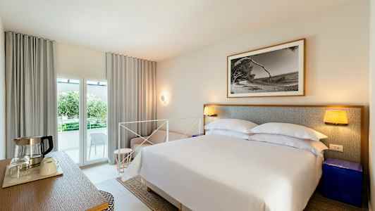 Soveværelse med dobbeltseng, natbord, billede på væggen og altan med udsigt. (AI-genereret tekst)