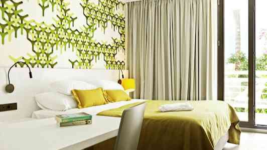 Moderne hotelværelse med grøn dekoreret væg og store vinduer. (AI-genereret tekst)