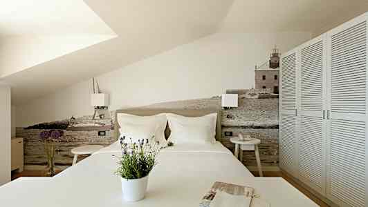 Soveværelse med en dekorativ væg med motiver af hav og bygninger. (AI-genereret tekst)