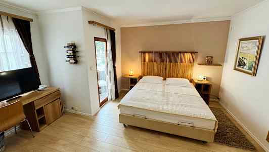 Billede af et hotelværelse med dobbeltseng, skrivebord og TV. (AI-genereret tekst)