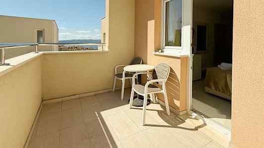 En altan med to stole og et bord, med udsigt til himlen og havet. (AI-genereret tekst)