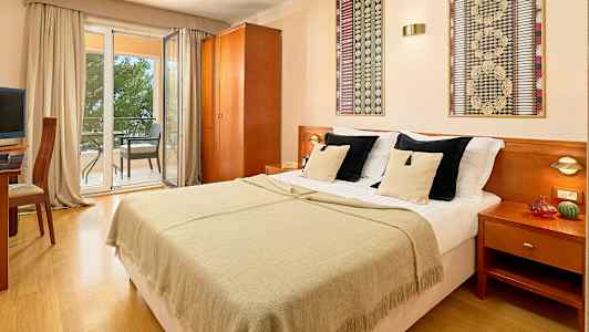 Dobbeltværelse med dobbeltseng, udsigt til altan med siddepladser. (AI-genereret tekst)