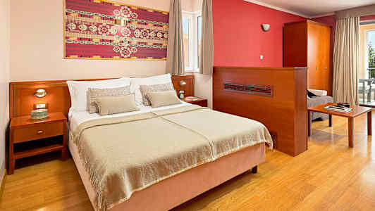 Hotelværelse med en dobbeltseng, natbord og kunst på væggen. (AI-genereret tekst)