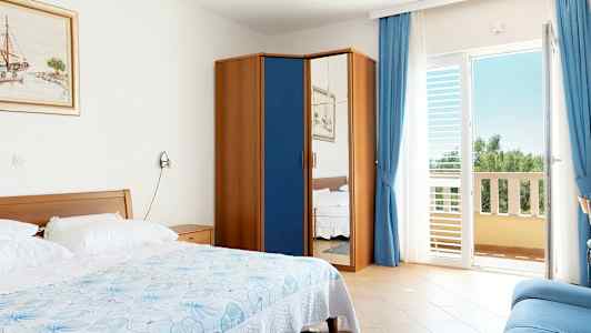 Et hotelværelse med en seng, et skab med spejldør og en altan. (AI-genereret tekst)