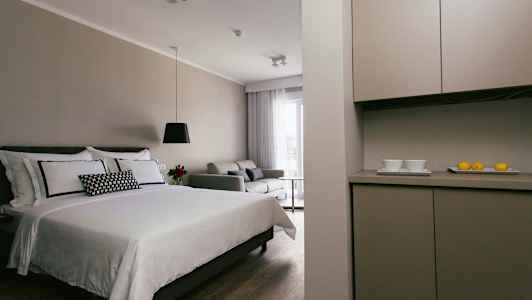 Moderne hotelværelse med en seng, sofa og køkkenområde. (AI-genereret tekst)