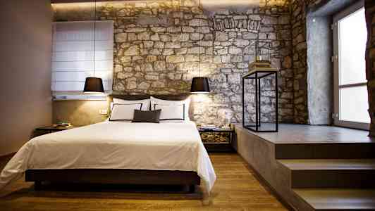 Et stilfuldt soveværelse med en seng og stenvæg. (AI-genereret tekst)