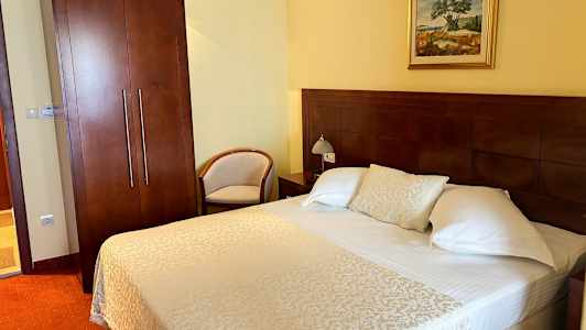 Hotelværelse med en dobbeltseng, natbord og garderobe. (AI-genereret tekst)