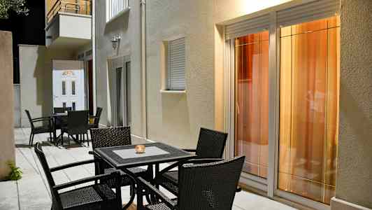 Havemøbler foran en bygning med vinduer og dør. (AI-genereret tekst)