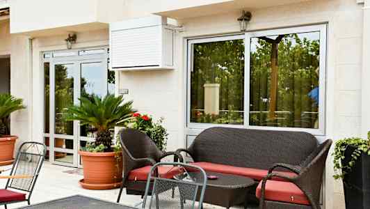 Udendørsområde med siddegruppe, grønne planter i potter og glasdøre. (AI-genereret tekst)