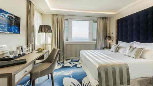 Et moderne hotelværelse med en dobbeltseng og skrivebord. (AI-genereret tekst)