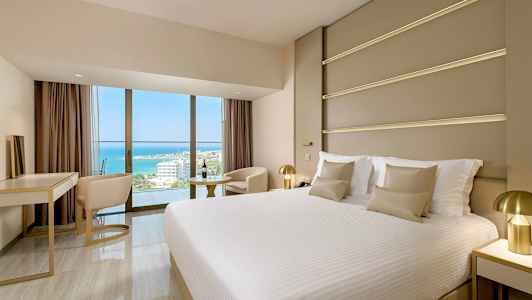 Et moderne hotelværelse med en stor seng og udsigt over havet. (AI-genereret tekst)