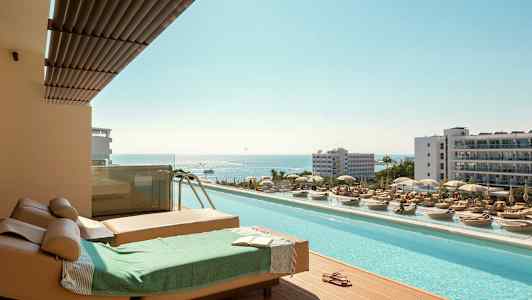 Liggestole og pool med udsigt over havet i en feriested. (AI-genereret tekst)