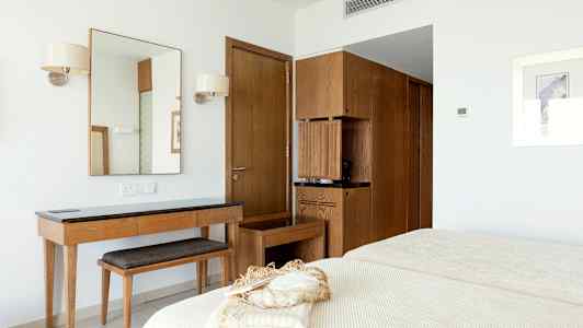 Et hotelværelse med et spejl, et træbord, hylder og en seng. (AI-genereret tekst)