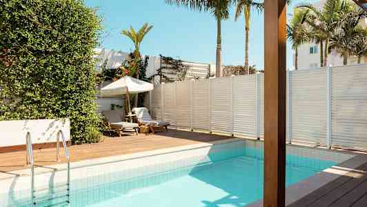 En swimmingpool med soldæk og liggestole i tropisk miljø. (AI-genereret tekst)