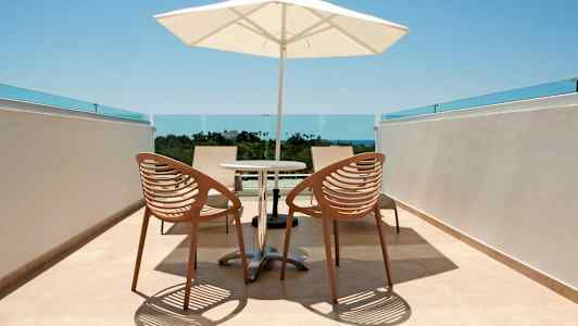 Billede af en terrasse med to stole, et bord og en parasol. (AI-genereret tekst)