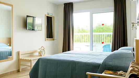 Et hotelværelse med en seng ved siden af en glasdør, der fører til en altan. (AI-genereret tekst)