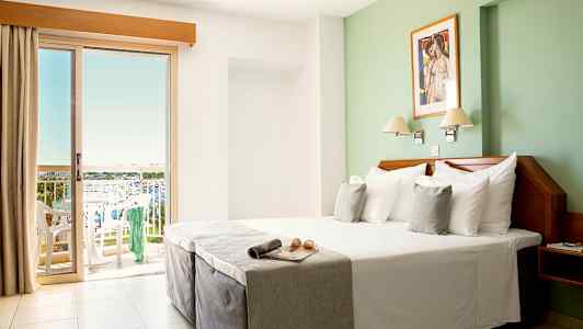 Hotelværelse med dobbeltseng og altan med udsigt. (AI-genereret tekst)