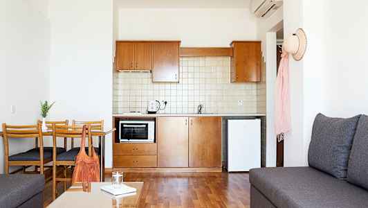 Et lille køkken med træmøbler og hvide vægge. (AI-genereret tekst)