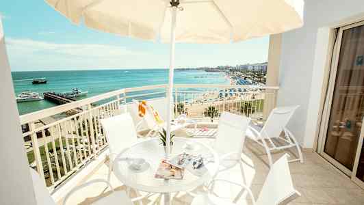 En altan med bord og stole, udsigt over stranden og havet. (AI-genereret tekst)